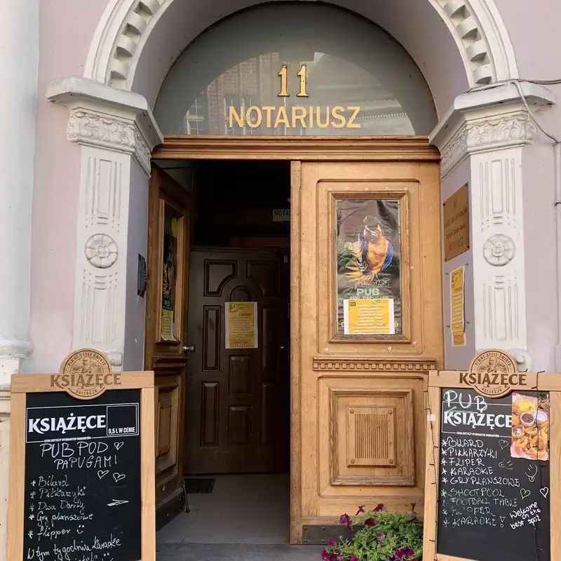 Zabytkowa brama z numerem 11 i tablicami pubu przy wejściu