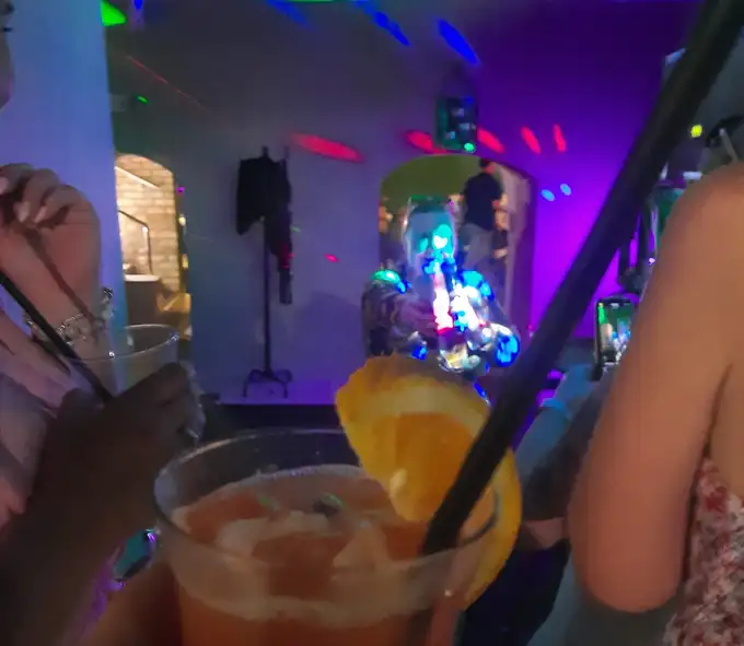 Neonowe światła na sali i drink w dłoni